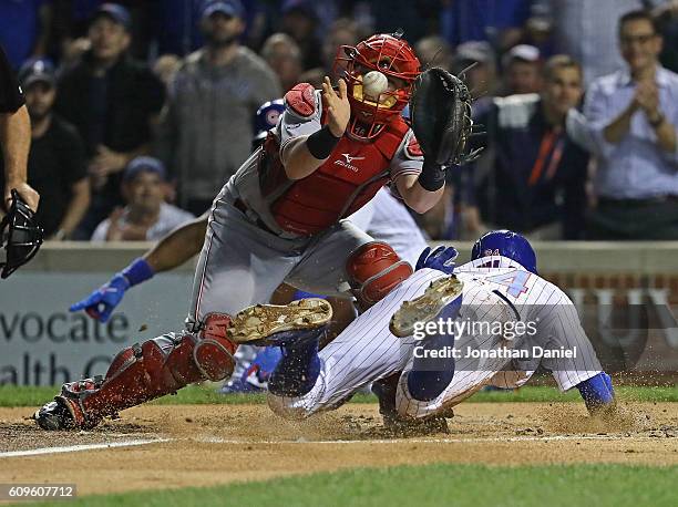 Dexter Fowler of the Chicago Cubs slides under Tucker Barnhart of the Cincinnati Reds to score a run in the 1st inning at Wrigley Field on September...