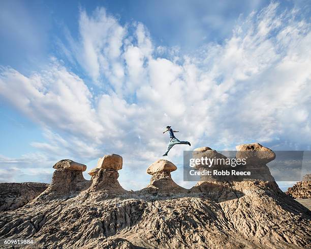 a man performing parkour outdoors on rock formations in the desert - rock terrain stockfoto's en -beelden