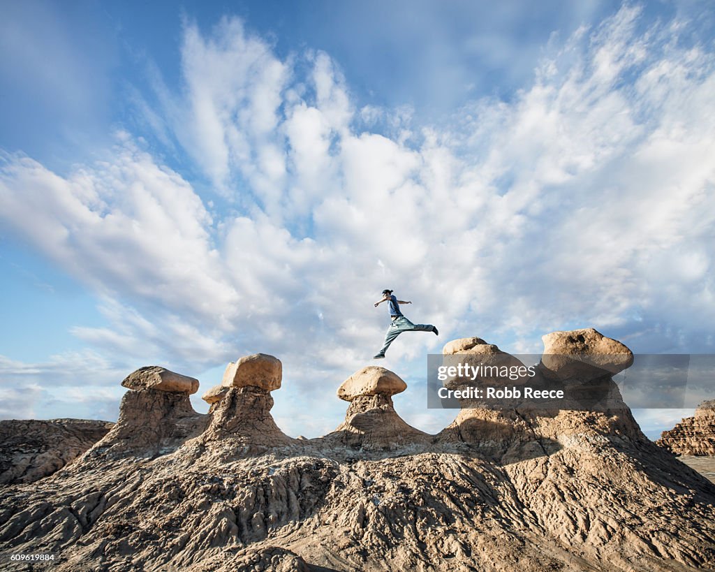 A man performing parkour outdoors on rock formations in the desert