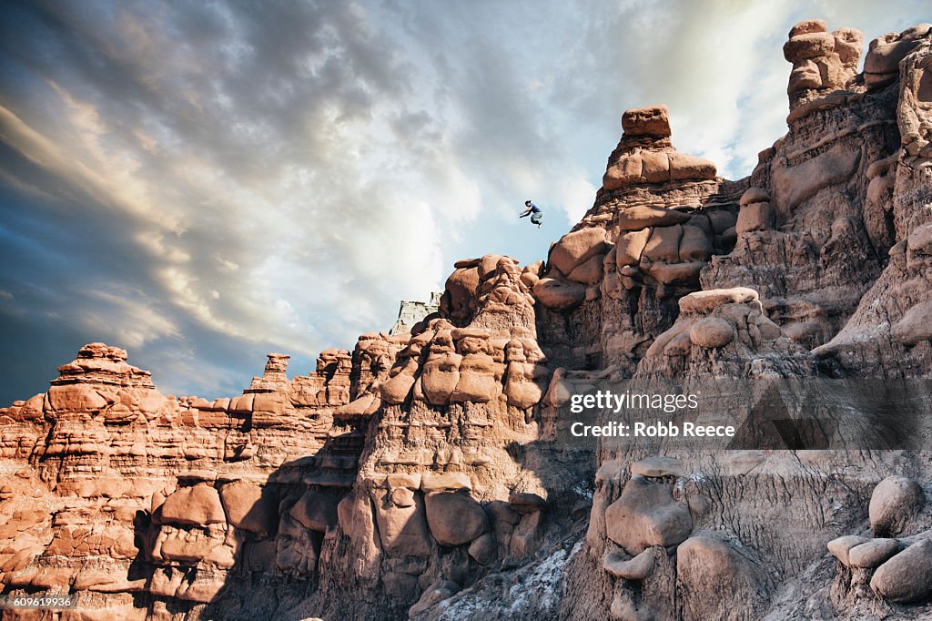 A man performing parkour outdoors on rock formations in the desert