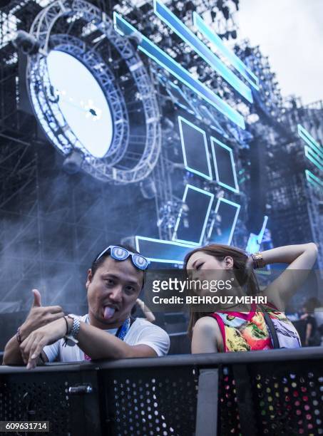 In this picture taken on September 18, 2016 a Japanese girl and guy gesture as they attend an electronic music show during the Japan Ultra Music...