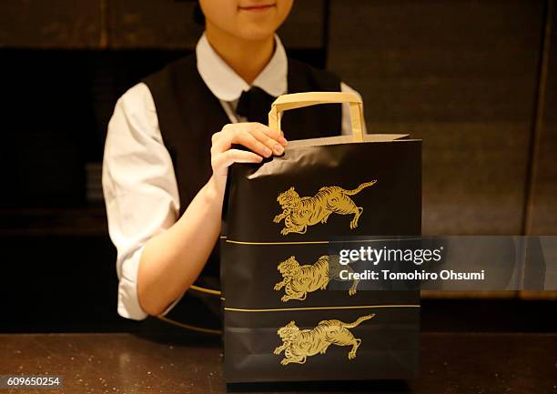 An employee holds a bag containing packages of Yokan or Japanese sweet bean past jelly at the Toraya Confectionery Co., Ltd. Store in the Isetan...