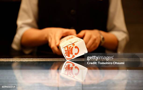 An employee demonstrates how to wrap a packaged bar of Yokan or Japanese sweet bean past jelly at the Toraya Confectionery Co., Ltd. Store in the...