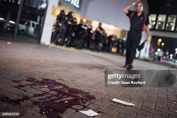 As police officers guard the garage entrance to the Omni Hotel, a man approaches blood on the sidewalk September 21, 2016 in Charlotte, NC. Protests...