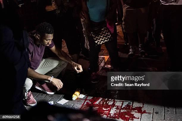 Man looks at blood on the sidewalk in front of the Omni Hotel September 21, 2016 in Charlotte, NC. Protests in Charlotte began on Tuesday in response...