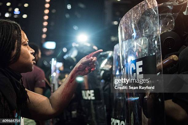 With blood covering her hand and arm, a woman points at a police officer on September 21, 2016 in Charlotte, NC. The North Carolina governor has...