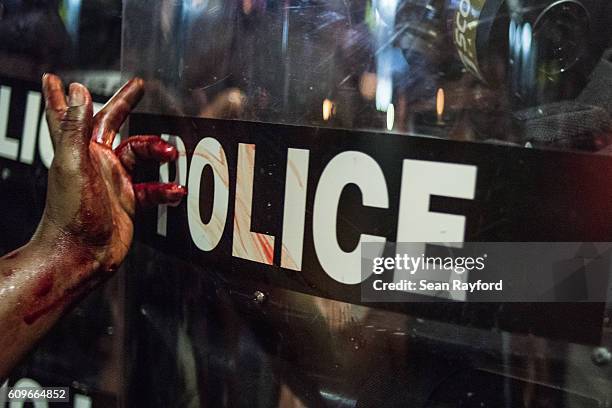 Woman smears blood on a police riot shield on September 21, 2016 in downtown Charlotte, NC. The North Carolina governor has declared a state of...