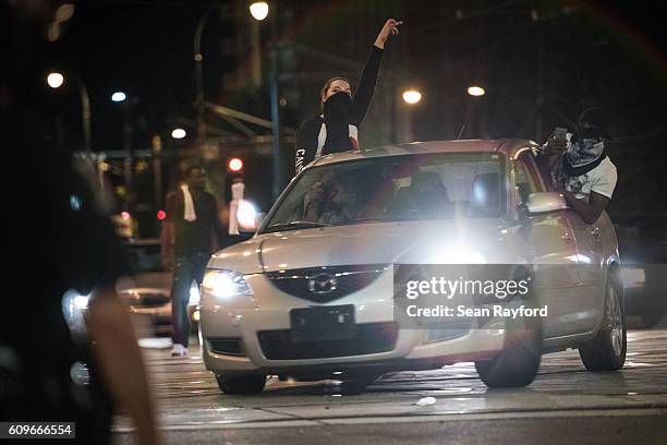 Demonstrators hang out car windows during protests September 22, 2016 in downtown Charlotte, NC. The North Carolina governor has declared a state of...