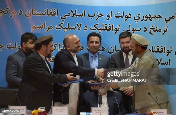 Afghan National Security Adviser, Hanif Atmar shakes hands with Amin Karim,, representative of Afghan warlord Gulbuddin Hekmatyar after signing a...