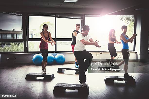 grupo de gente haciendo ejercicios aeróbicos en el gimnasio - un escalón fotografías e imágenes de stock