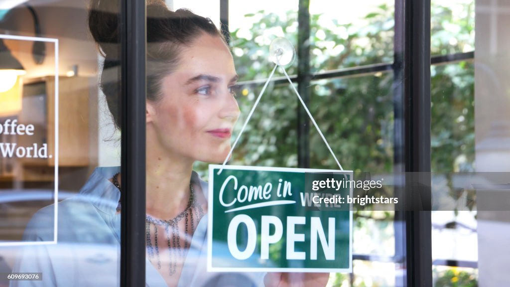 Female coffee shop owner opening the shop