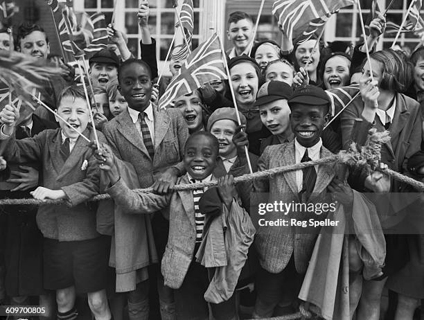 Crowd of children waving union jacks as Queen Mary, wife of King George V, visits Brixton in south London to open the new Lambeth Town Hall, 14th...