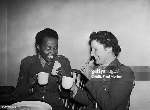 Lance Corporal Adina Williams of the British Auxiliary Territorial Service , has a cup of tea and a sandwich with another member of her unit, UK,...