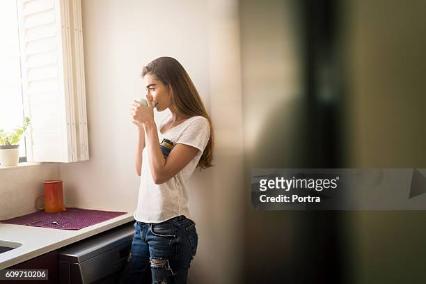 mulher bebendo café enquanto estava de pé pela janela - coffee drink - fotografias e filmes do acervo