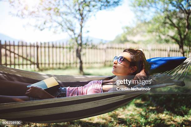 giovane donna rilassante in amaca - libri gialli estate foto e immagini stock