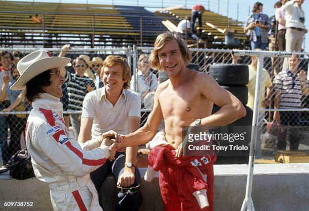 Grand Prix West: Great Britain James Hunt of McLaren-Ford team on the sidelines, bare-chested, shaking hands with racer Arturo Merzario before race...