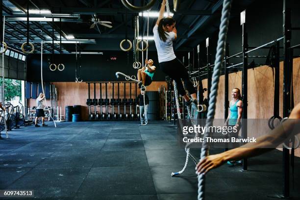 group of friends climbing ropes in gym gym - crossfit stockfoto's en -beelden