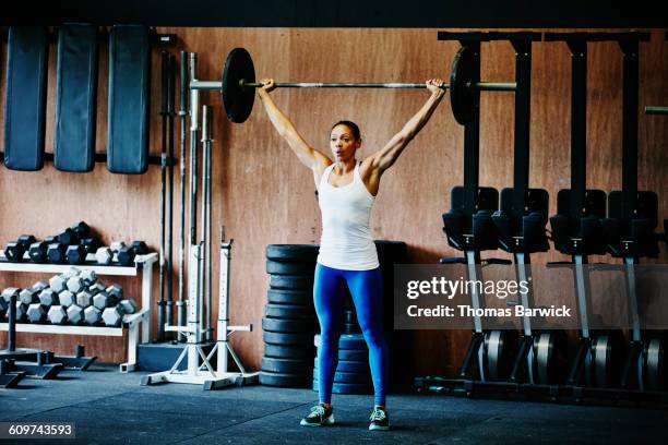 woman pressing barbell overhead during workout - cross training stock pictures, royalty-free photos & images