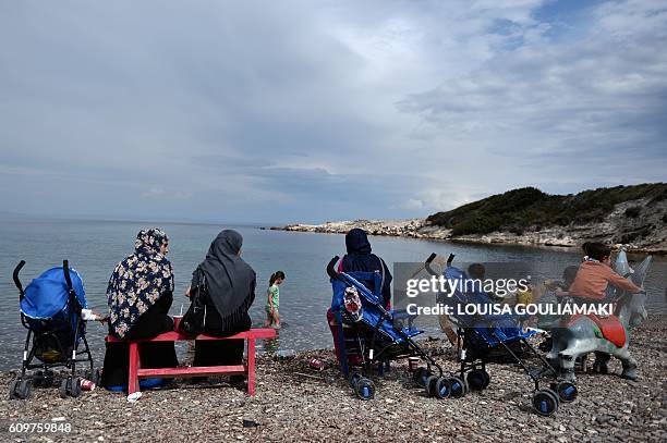 Familes rest on a beach at an unofficial migrant camp, run by activists on the island of Lesbos on September 22, 2016. / AFP / LOUISA GOULIAMAKI