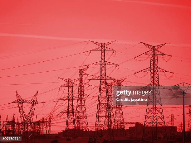 towers of high voltage lines at sunset - brick cathedral stock-fotos und bilder