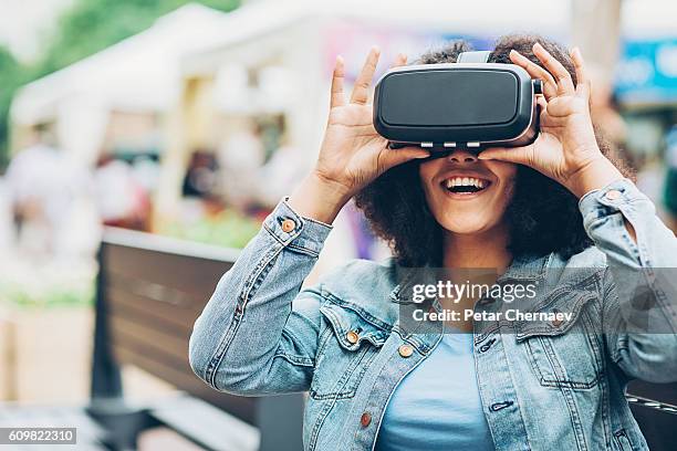 lächelndes mädchen, das durch ein virtual-reality-headset schaut - vr goggles woman stock-fotos und bilder