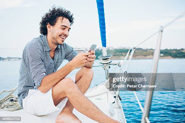 texting in the sea - male sailing stockfoto's en -beelden