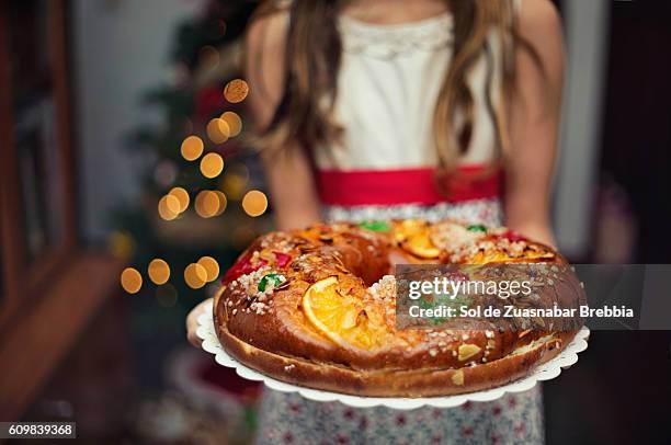 cute little girl holding a christmas sweet at home. - rosca de reyes fotografías e imágenes de stock
