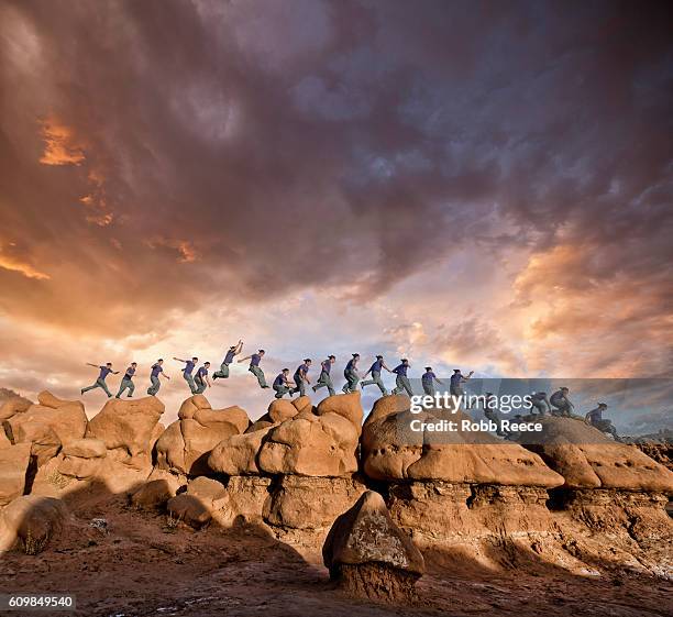 a man parkour running outdoors on rock formations in the desert - continuité photos et images de collection