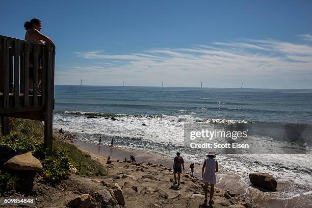 Tourists look out from a beach at the GE-Alstom Block Island Wind Farm stands 3 miles off of Block Island on September 22, 2016 New Shoreham, Rhode...