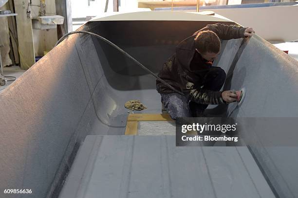 Worker sands the interior of a fiberglass boat hull at a King's Fiberglass Pty. Ltd. Facility in Melbourne, Australia, on Wednesday, Aug. 17, 2016....