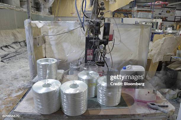 Spools of fiberglass gun roving sitting on a table are fed into a chopper gun, unseen, at a King's Fiberglass Pty. Ltd. Facility in Melbourne,...