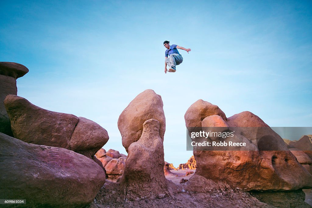 A man performing parkour outdoors on rock formations in the desert