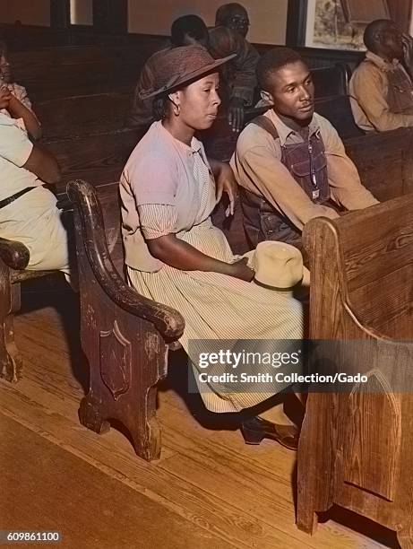 Male and female African-American farmers sitting in pews at a church during a Farm Security Administration meeting of borrowers in a church near...