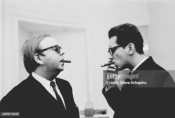 Art curator and historian Henry Geldzahler smokes cigars with American artist Frank Stella, New York, New York, 1965.