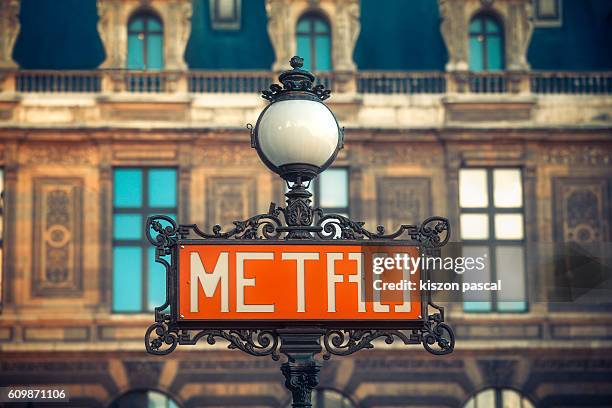 red metro sign with street lamp and traditional buildings ( paris , france ) - subway paris stock-fotos und bilder