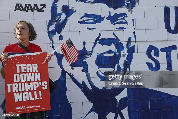 An activist protesting against U.S. Republican presidential candidate Donald Trump stands next to a wall of cardboard blocks showing Trump that...