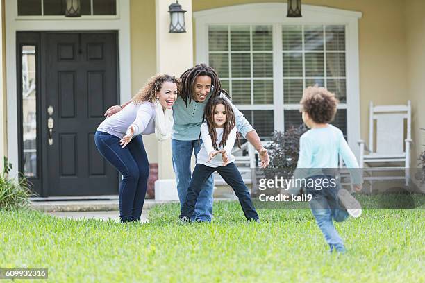 gemischte rasse familie spielt im vorgarten von zu hause - two kids playing with hose stock-fotos und bilder