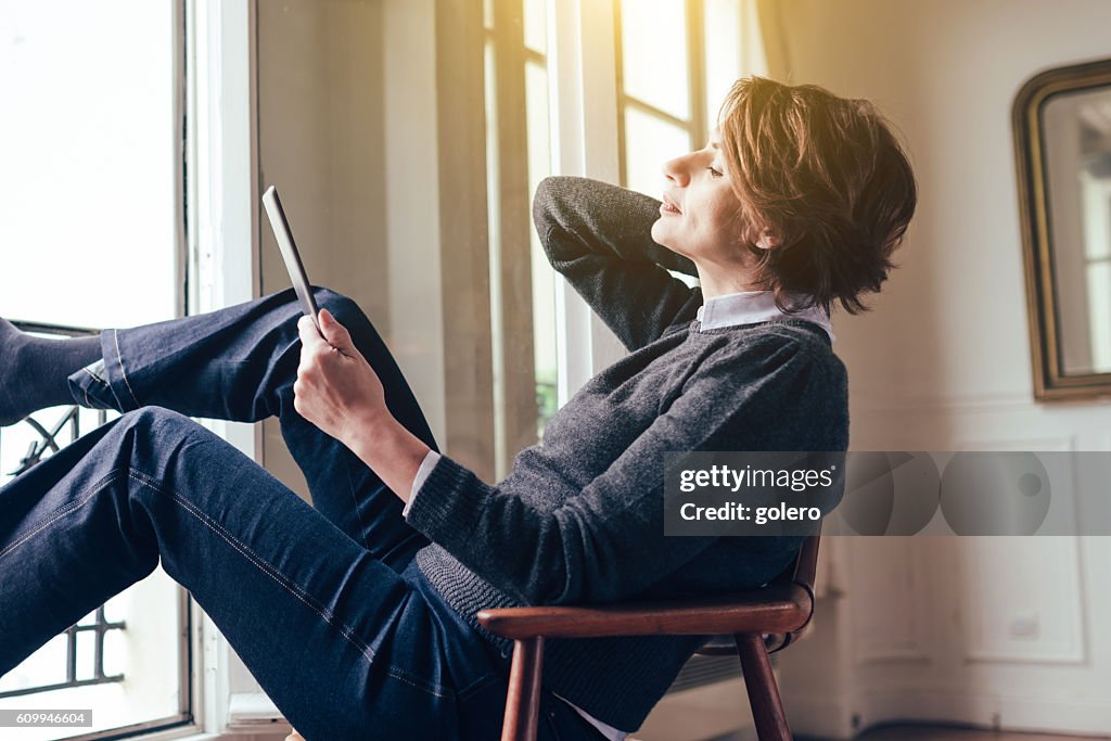 Beautiful  french woman relaxing with tablet in Paris apartment