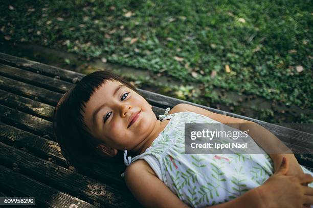 adorable mixed race toddler girl lying down and smiling at camera - child lying down stock pictures, royalty-free photos & images