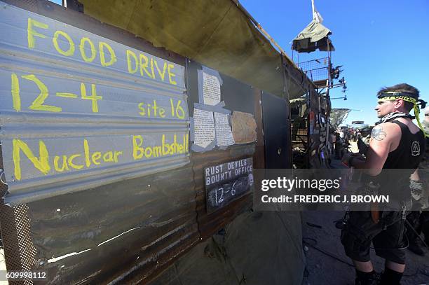 Man reads a sognboard as festival goers attend day two of Wasteland Weekend in the high desert community of California City in the Mojave Desert,...