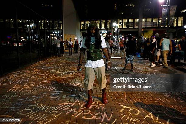 An activist adds to a growing memorial of names written on the sidewalk outside the Omni Hotel as residents and activists march nearby amid heavy...