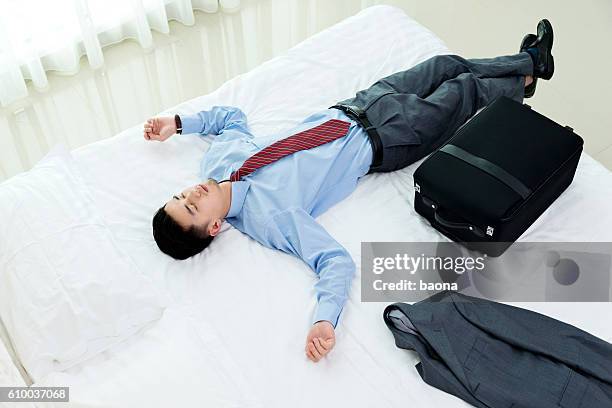 uomo d'affari sdraiato a letto con i bagagli - supino foto e immagini stock