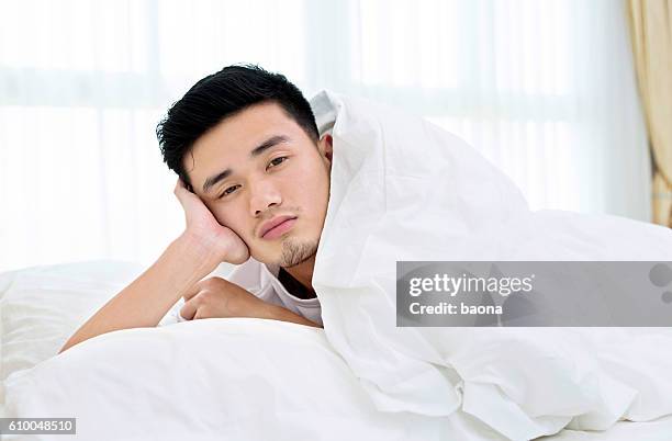 verschlafener mann im bett - auf dem bauch liegen stock-fotos und bilder
