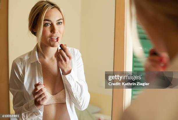 young woman doing her makeup while getting dressed - lipgloss bildbanksfoton och bilder