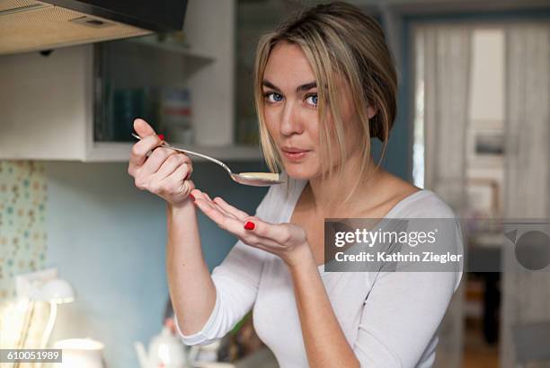 young woman cooking, testing pasta - tasting cooking stock pictures, royalty-free photos & images