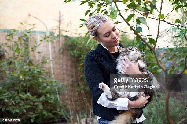 young woman cuddling her big fluffy cat - cat lady stock pictures, royalty-free photos & images