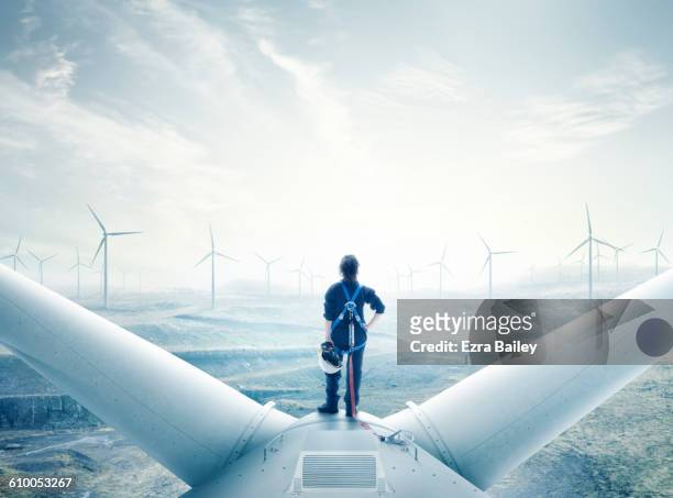 female engineer standing on top of a wind turbine. - majestic clouds stock pictures, royalty-free photos & images
