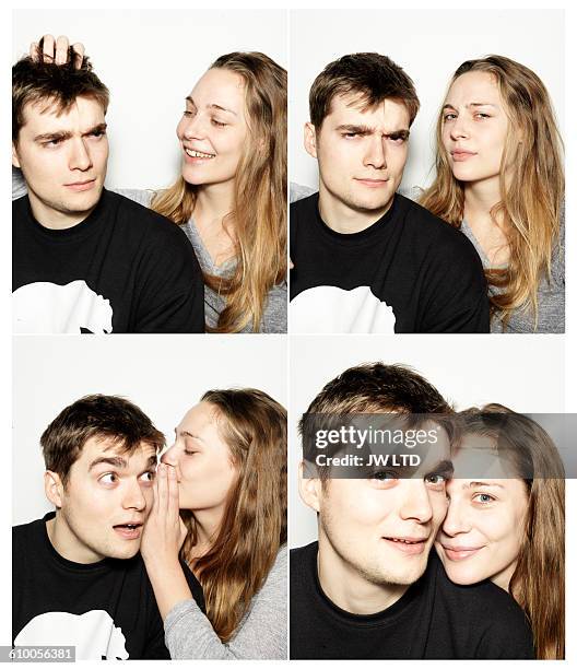 young couple having fun in photo booth - woman whisper to man stockfoto's en -beelden