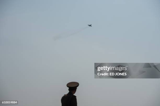 Soldier watches as a Mig-29 aircraft performs a fly-by during the first Wonsan Friendship Air Festival in Wonsan on September 24, 2016. Just weeks...