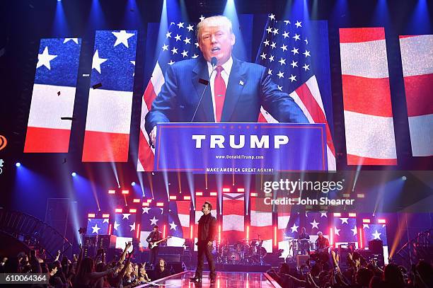 An image of businessman/politician Donald J. Trump is projected on a screen while recording artists The Edge, Bono, Larry Mullen Jr., and Adam...